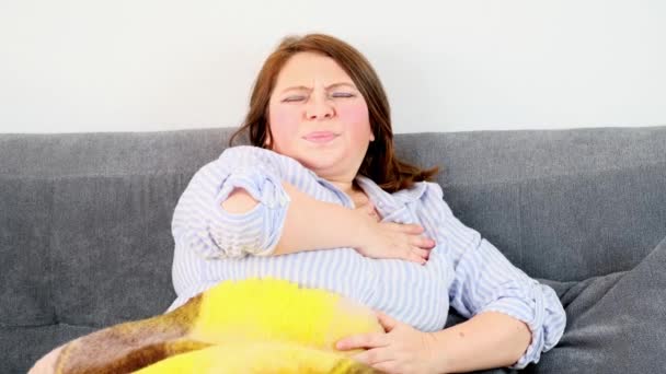 Mulher Adulta Está Sentada Sofá Segurando Mão Lado Esquerdo Peito — Vídeo de Stock