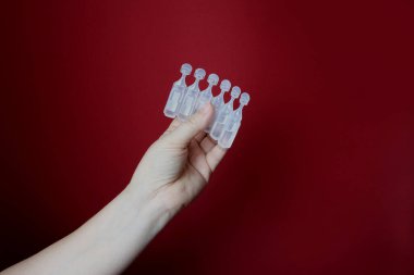 Yakın plan kadın eli elinde ilaç paketi kırmızı zemin üzerinde aşı virüse karşı aşı konsepti, koronavirüs, COVID-19