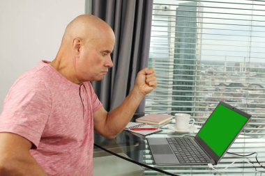 Adam bir dizüstü bilgisayarın arkasında çalışıyor. Modern Avrupa şehrinin penceresinin önündeki bir ofiste boş ekranla. İş fikirleri konsepti, işyeri.