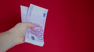 Kadın elleri kırmızı zemin üzerinde kağıt euro banknotları tutuyor, bir tomar para, nakit konsepti, ödemeler, tasarruf