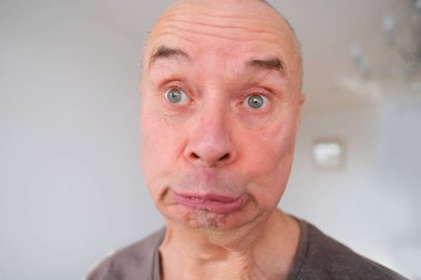 Avrupalı yaşlı bir adamın yüzü, yaşlanan cildinde kırışıklıklar, çıplak dişler, ekşitmeler, zihinsel sağlık, kozmetoloji, yaşla ilgili değişiklikler.