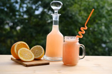 Sürahide taze sarı meyve püresi ve eski ahşap masada bardak, dilimlenmiş portakal, ferahlatıcı taze narenciye içecekleri, vejetaryen yemeği konsepti. 