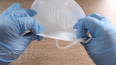 Kadın doktor eli, eczacı koruyucu solunum cihazını yüksek dereceli koruma sınıfı FFP2 ile masaya koydu, beyaz maskenin kalitesini gösteriyor, COVID-19 konsepti