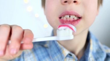 çocuk, 6-7 yaşlarındaki çocuk dişlerini özenle fırçalıyor ve renkli çocuk macunu, diş konsepti, ağız hijyeni, günlük sabah rutini