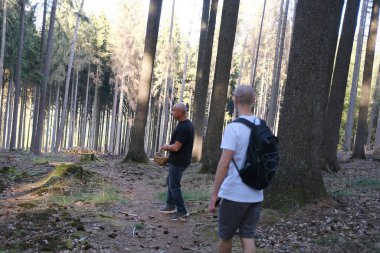 Ormanda iki adam yürüyor, sırtlarında bir sırt çantası, doğa koruma kavramı, ekolojik denge, turizm, seyahat, aktif yaşam tarzı.