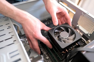 Genç erkek ustanın elleri, işlemci için bakır ısı borularıyla soğutucuyu, bilgisayarın diğer parçalarını, ekipman onarımı, montajı, kişisel bilgisayar güncellemesi konseptini, kutuya yerleştirir.