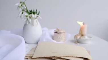İlk bahar çiçekleri, kartanesi, vazodaki Galanthus, bir melek figürü, bir yığın eski fotoğraf, mum, aile ağacı konsepti, soy ağacı, atalarımızın hafızası.