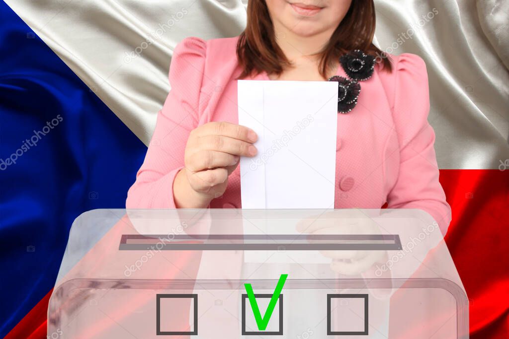 woman voter in a smart pink jacket lowers the ballot in a transparent ballot box against the background of the national flag of the country of Czech Republic, concept of state elections, referendum