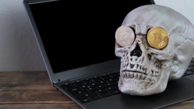 Klavyede insan kafatası modeli, göz çukurlarında metal bitcoin, kripto para madenciliği konsepti, yaşam, ölüm, parasal işlem riski