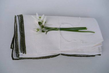 Beyaz keten kumaş, peçete çeşitli katmanlarda sarılmış, ince bir iplikle bağlanmış bir kar tanesi hafif bir zemin üzerinde yatıyor, doğal çevre dostu kumaş konsepti.