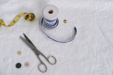 beyaz keten peçete, el yapımı dantelle budanmış, çeşitli katmanlarda sarılmış, narin kar tanesi çiçeği, makas, düğmeler, kurdele ışık masasında, dikiş konsepti