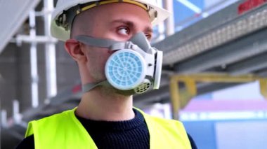 İnşaat alanındaki teftiş sırasında beyaz şapkalı ve koruyucu solunum cihazlı genç erkek ustabaşı, işçi veya mimar, binaların ve yapıların onarımını izleme konsepti,