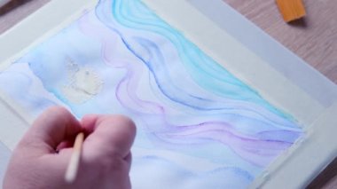 Kadın ressamın eli, renkli boyalar, mavi, eflatun dalgaları, arka plan, beyaz desenli kağıda yayılmış soyut lekeler, suluboya resim, yaratıcı sanat konsepti, sanat terapisi