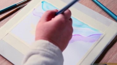 Kadın ressamın eli, renkli boyalar, mavi, eflatun dalgaları, arka plan, beyaz desenli kağıda yayılmış soyut lekeler, suluboya resim, yaratıcı sanat konsepti, sanat terapisi