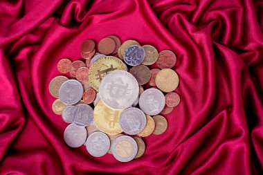Metal para kaydırağı, farklı ülkelerin para birimleri, kırmızı lüks kumaş üzerindeki bitcoinler, artan ve tasarruf eden para kavramı.