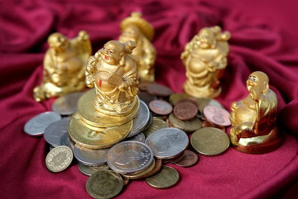 slide of metal coins, currencies of different countries, bitcoins on a red luxury drapery, five Japanese hotei god of wealth, symbol of prosperity, concept of saving money