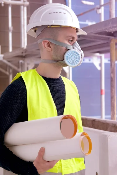 young male builder foreman, worker or architect in white hardhat and protective respirator during inspection in construction site, concept of monitoring repair of buildings, structures