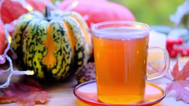 Çay fincanındaki çay fincanının kaplaması tabağın üzerindeki ahşap masa yeşil arka plan, balkabakları yalan, mumlar yanıyor, sabah konsepti, mevsimlik sonbahar havası, sağlıklı yaşam tarzı