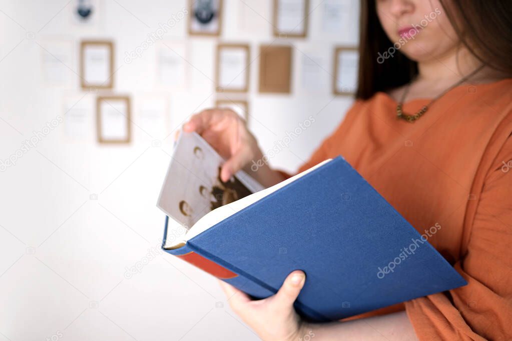 young european woman with long hair holds a thick book in a blue cover in her hands, flips through the pages, concept of fiction, nonfiction, reading, developing hobby