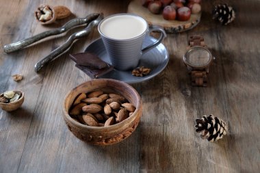 Bir fincan kahve, farklı türde fındık, ceviz, fındık, eski ahşap masa tahtalarındaki badem, yenilebilir çekirdek, gıda konsepti, şekerleme malzemesi.