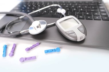 Tıbbi stetoskop, yedek iğneler, glukometre, beyaz arka planda dizüstü bilgisayar klavyesi, evdeki kan şekerini ölçmek için ekipman