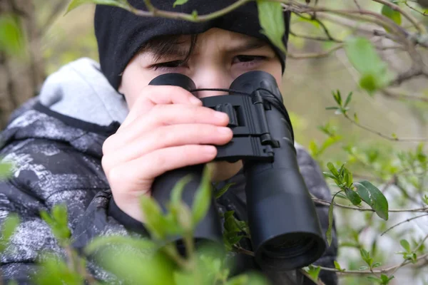 男の子 10歳のストーカーは公園で黒双眼鏡を通して見て スパイ 秘密を狩り 森の中で失われ 危険な冒険 監視の概念 人々と動物の観察 — ストック写真