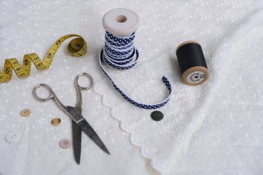 beyaz keten peçete, el yapımı dantelle budanmış, çeşitli katmanlarda sarılmış, narin kar tanesi çiçeği, makas, düğmeler, kurdele ışık masasında, dikiş konsepti