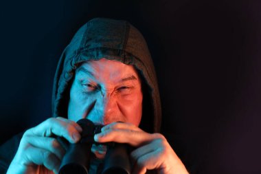 Orta yaşlı bir adam, kapüşonlu bir sapık karanlıkta siyah dürbünle bakar, dikizler, komşuların kişisel sırlarını yasadışı olarak takip eder, endüstriyel casusluk kavramını, gözetlemeyi,