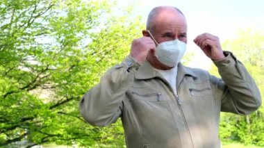 Yetişkin Avrupalı 60 yaşında bir erkek yeşil parkta maske takarak yürüyor, yüksek derecede korunan koruyucu solunum cihazı FFP2, Avrupa 'da COVID-19 Coronavirus, grip, enfeksiyon