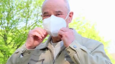 Yetişkin Avrupalı 60 yaşında bir erkek yeşil parkta maske takarak yürüyor, yüksek derecede korunan koruyucu solunum cihazı FFP2, Avrupa 'da COVID-19 Coronavirus, grip, enfeksiyon