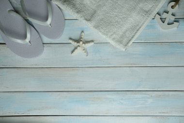 Havlu, denizyıldızı, çapa, beyaz plaj terlikleri açık mavi ahşap arka plan, yaz zamanı konsepti, tatil zamanı, seyahat, plaj deneyimi