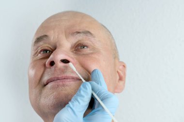 Eldivenli erkek doktorun yakın çekimi, analiz için burundan alınan örnek, hızlı nazal test kovid-19, viral hastalığın erken teşhisi, SARS-CoV-2 salgını, koronavirüs...