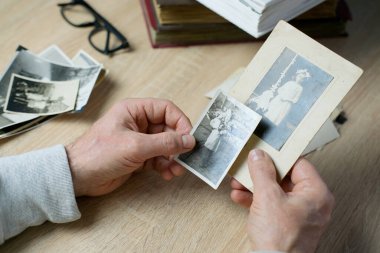 Yakın plan erkek, 1940-1950 yılları arasında çekilmiş eski vintage fotoğraflarını tutuyor. Aile ağacı, soy ağacı, çocukluk anıları, atalarımızın hafızası.