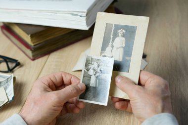 Yakın plan erkek, 1940-1950 yılları arasında çekilmiş eski vintage fotoğraflarını tutuyor. Aile ağacı, soy ağacı, çocukluk anıları, atalarımızın hafızası.