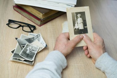 Yakın plan erkek, 1940-1950 yılları arasında çekilmiş eski vintage fotoğraflarını tutuyor. Aile ağacı, soy ağacı, çocukluk anıları, atalarımızın hafızası.