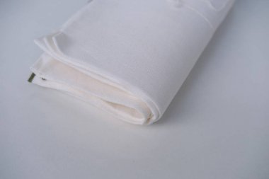 Beyaz keten kumaş, peçete çeşitli katmanlara sarılmış, hafif bir zemin üzerinde yatıyor, doğal çevre dostu kumaş konsepti.