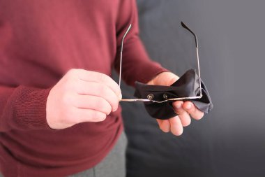 Genç adam özel siyah bir peçeteyi ince çerçevelere koyuyor. Miyop, vizyon, insan sağlığı kavramı.
