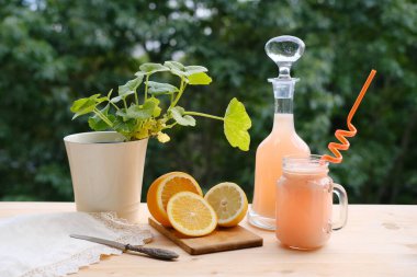 Sürahide taze sarı meyve püresi ve eski ahşap masada bardak, dilimlenmiş portakal, ferahlatıcı taze narenciye içecekleri, vejetaryen yemeği konsepti. 