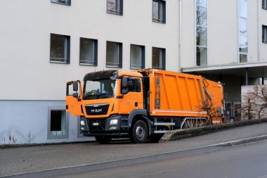 LUCERNE, SWitzERLAND - Ocak 2021: Turuncu kargo çöp kamyonu, çöp bidonları, atık geri dönüşüm konsepti, caddelerde trafik güvenliği düzenlemesi konsepti