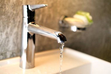 Su krom kaplama bir musluktan ince bir akarsu döker, banyo içi, sağlıklı yaşam biçimi, temizlik, sağlık, tedavi, su kaynaklarından tasarruf etme kavramı.
