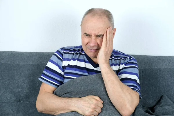 Viejo Hombre Calvo Sentado Sofá Presionando Una Almohada Estómago Cara —  Fotos de Stock