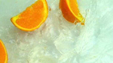 Süper yavaş çekimde portakal dilimi suya düşüyor, su sıçrıyor, sinek sıçrıyor, vejetaryen diyeti kavramı, sağlıklı yemek, sıcağın içinde tazeleniyor.