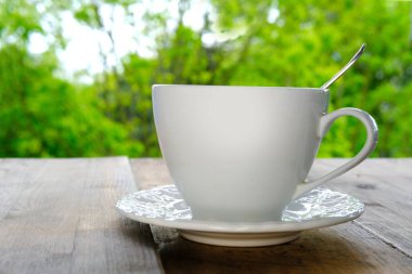 Yeşil bir yaz bahçesine karşı açık ahşap bir masada sıcak kokulu kahve, çay, kapuçino, açık hava çayı, iyi hava, kahve molası.