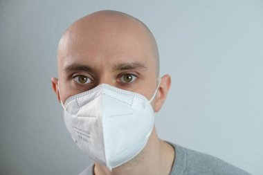 Beyaz maskeli, koruyucu solunum cihazlı yüksek dereceli koruma sınıfı FFP2, Avrupa 'da COVID-19 Coronavirüs, düzgün görünüyor, insani duygular kavramı