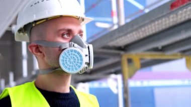 İnşaat alanındaki teftiş sırasında beyaz şapkalı ve koruyucu solunum cihazlı genç erkek ustabaşı, işçi veya mimar, binaların ve yapıların onarımını izleme konsepti,