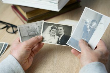 Yakın plan erkek, 1940-1950 yılları arasında çekilmiş eski vintage fotoğraflarını tutuyor. Aile ağacı, soy ağacı, çocukluk anıları, atalarımızın hafızası.
