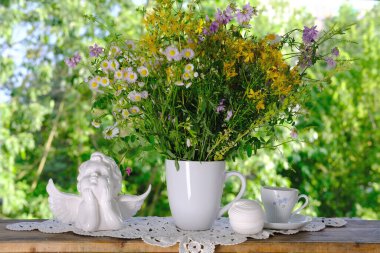 Bir fincan çay, güzel bir buket kır çiçeği masada el yapımı dantel beyaz altlık, yaz zamanı konsepti, bahçede çay içmek.