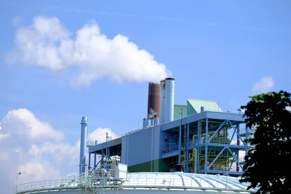 large plant, factory, modern chemical production, smoke flies from the pipes into the blue sky, steam, the concept of environmental pollution, harmful emissions into the atmosphere