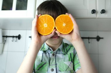 çocuk, 8-10, çocuk evde mutfakta oturuyor, göz yerine sulu sarı portakallar, kafa üstü, çocuk diyeti konsepti, sağlıklı yiyecekler.