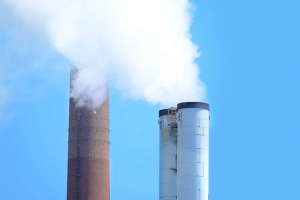 large plant, factory, modern chemical production, smoke flies from the pipes into the blue sky, steam, the concept of environmental pollution, harmful emissions into the atmosphere
